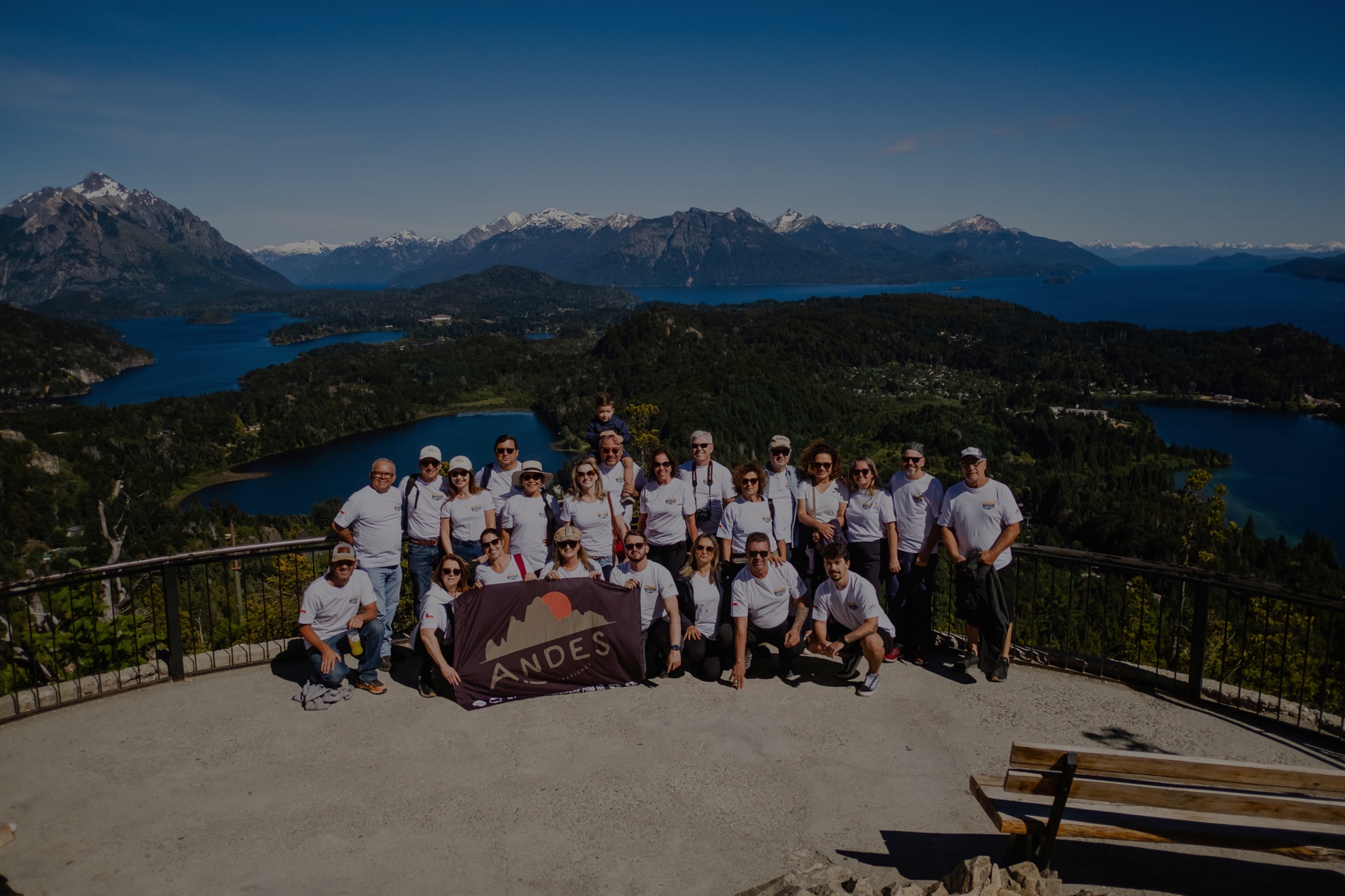 Grupo de viajantes com a bandeira da Andes Experience num mirante de Bariloche